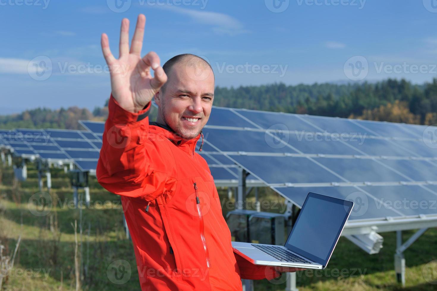 engenheiro usando laptop no campo de planta de painéis solares foto