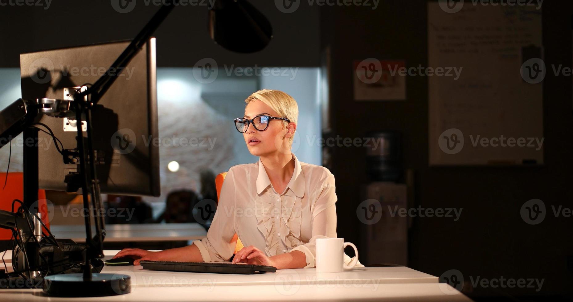 mulher trabalhando no computador no escritório escuro foto