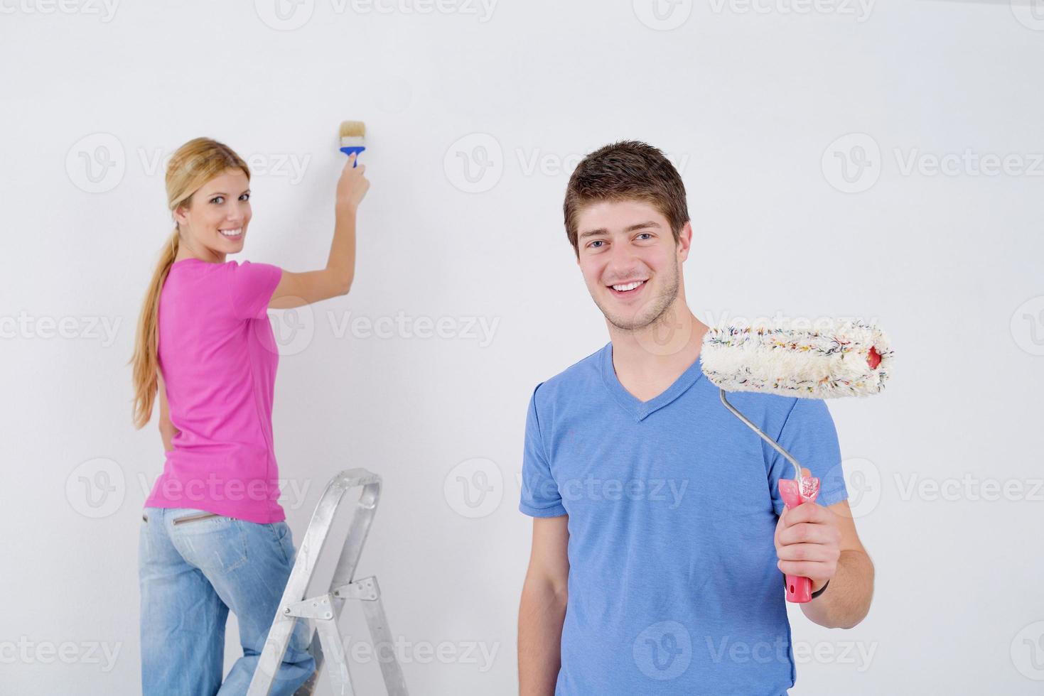 casal feliz pinta parede em casa nova foto