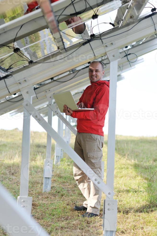 engenheiro usando laptop no campo de planta de painéis solares foto