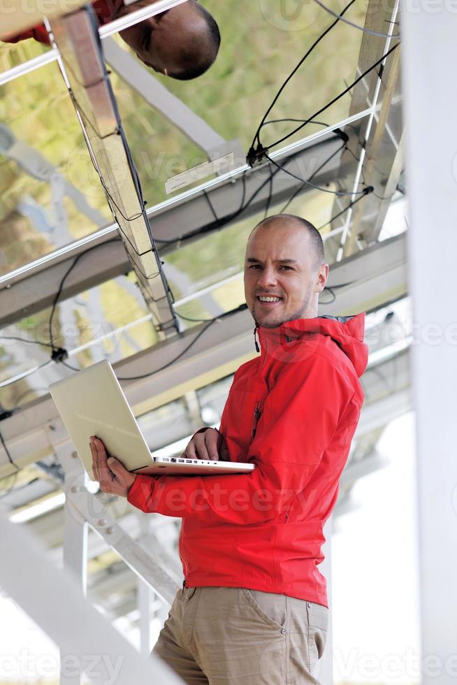 engenheiro usando laptop no campo de planta de painéis solares foto