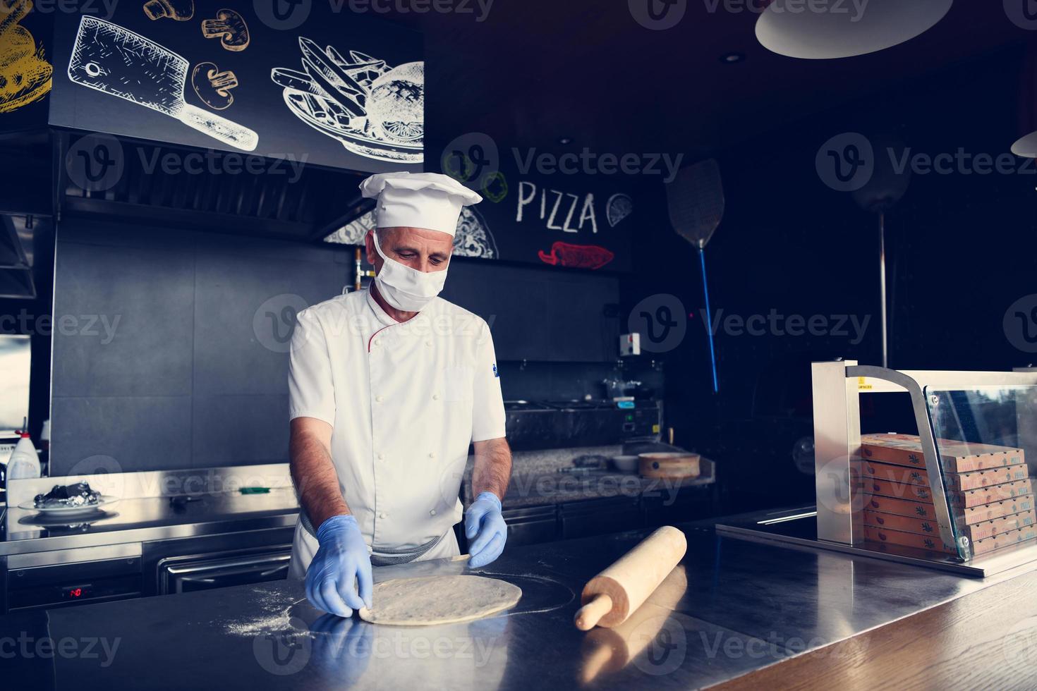 chef com máscara facial protetora de coronavírus preparando pizza foto