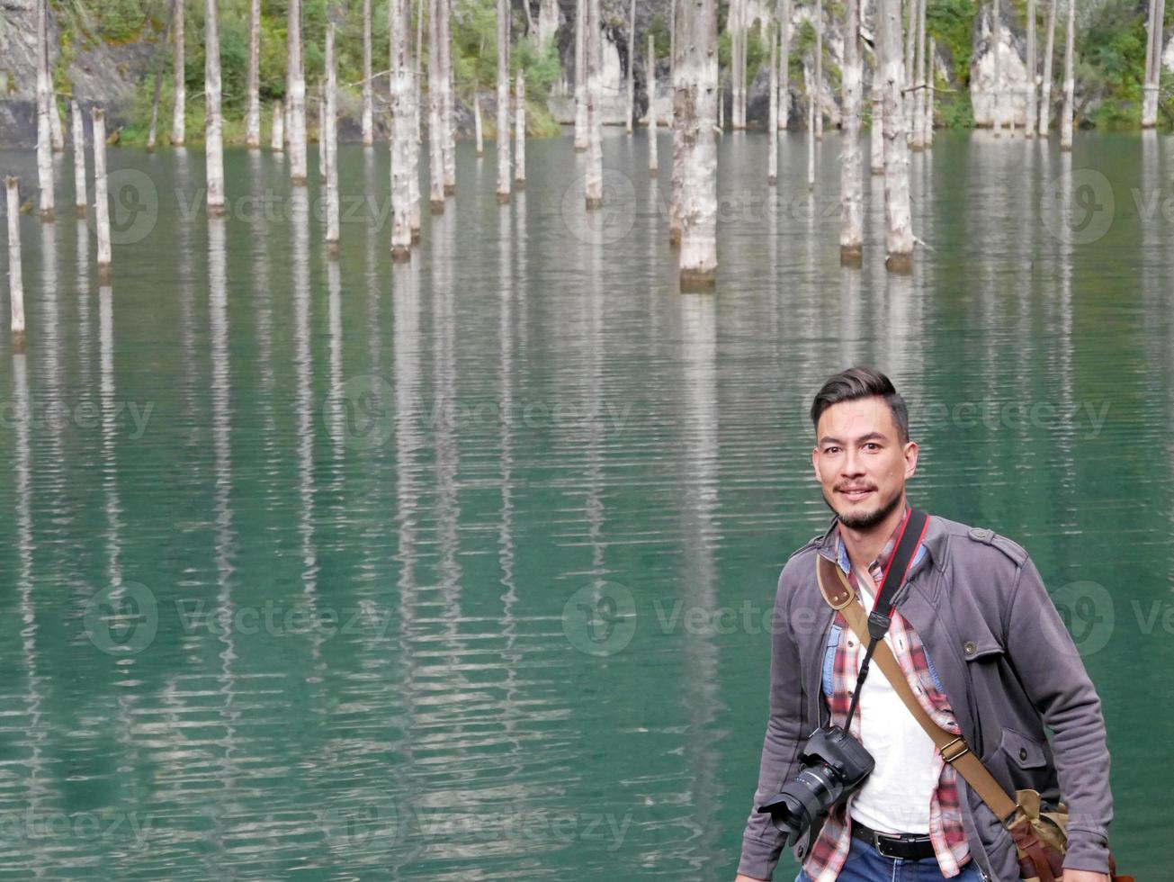 homem de pé na frente de troncos nus de árvores no lago kaindy no cazaquistão foto