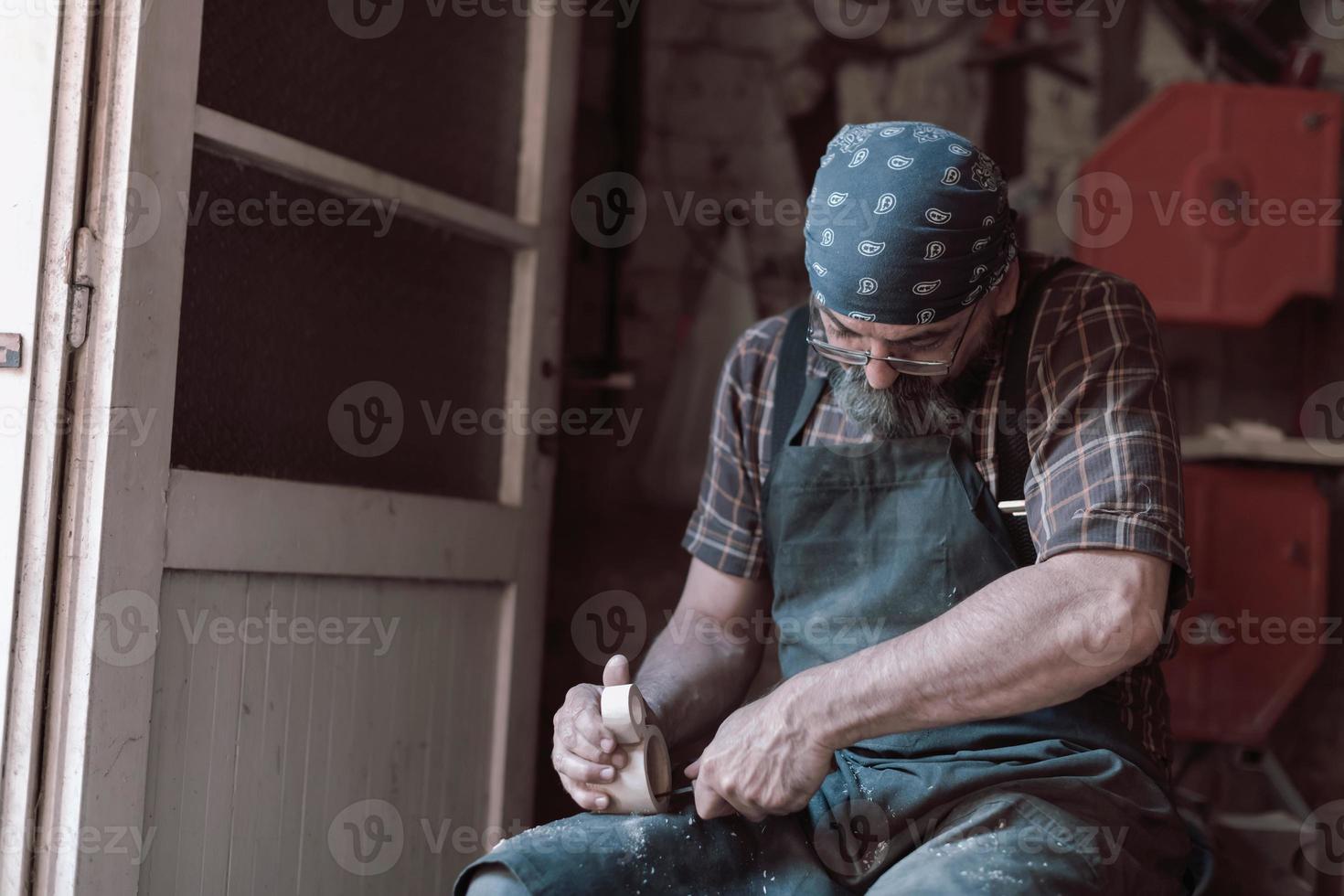 mestre de artesanato de colher em sua oficina com produtos artesanais de madeira e ferramentas trabalhando foto