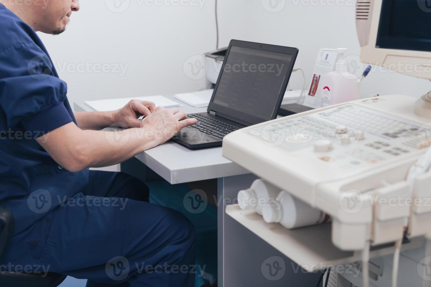 médico ortopedista examinando a imagem de raio-x na mesa na clínica no computador portátil foto