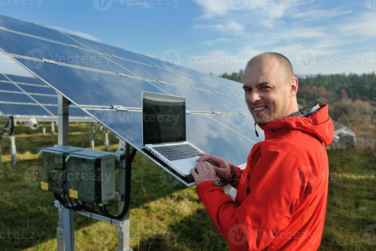 engenheiro usando laptop no campo de planta de painéis solares foto