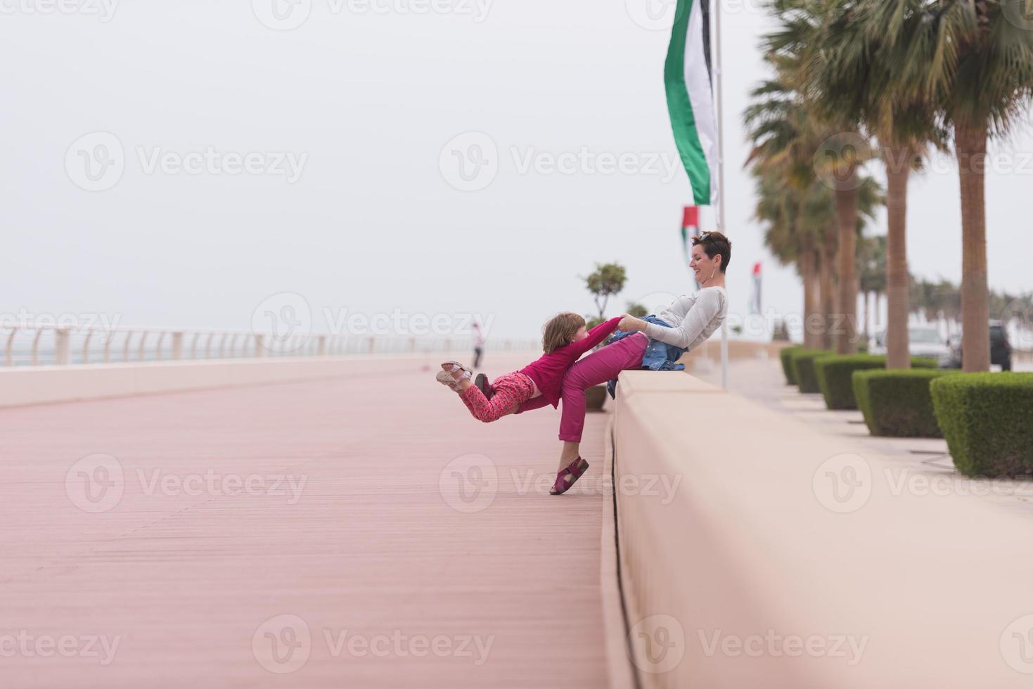 mãe e menina bonitinha no passeio à beira-mar foto