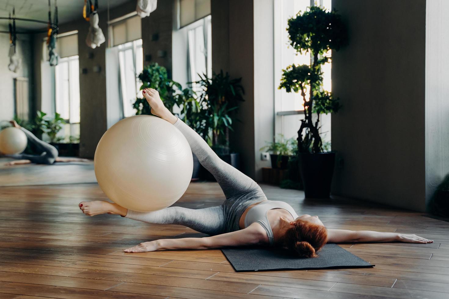 mulher fazendo exercícios abdominais com bola fit no tapete de ioga foto