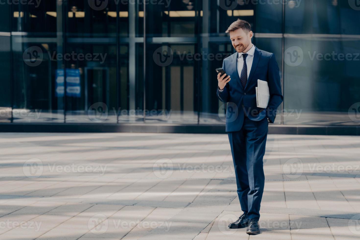 jovem empresário feliz com mensagens de jornal no smartphone ao ar livre foto