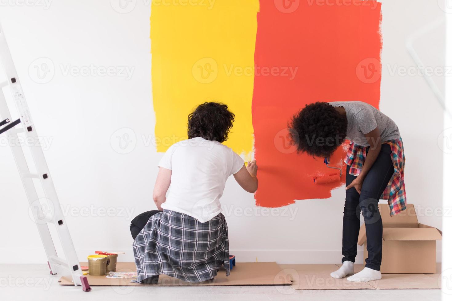 casal multiétnico pintando parede interior foto