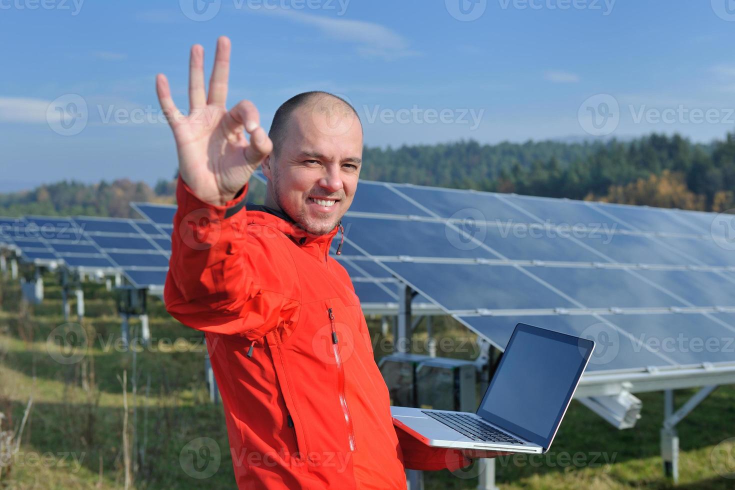 engenheiro usando laptop no campo de planta de painéis solares foto