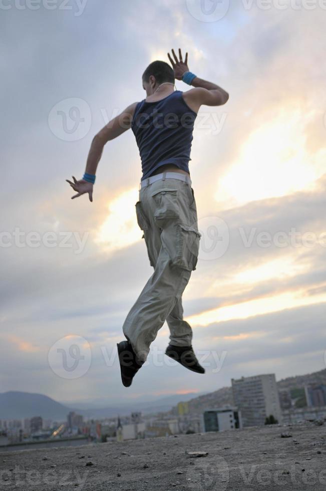 jovem dançando e pulando no topo do prédio foto