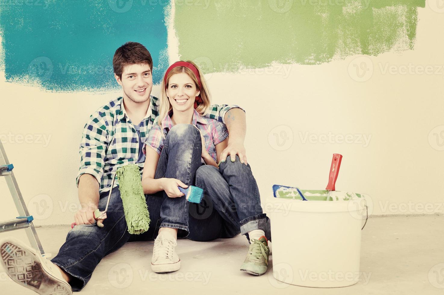 casal jovem feliz relaxando depois de pintar em casa nova foto