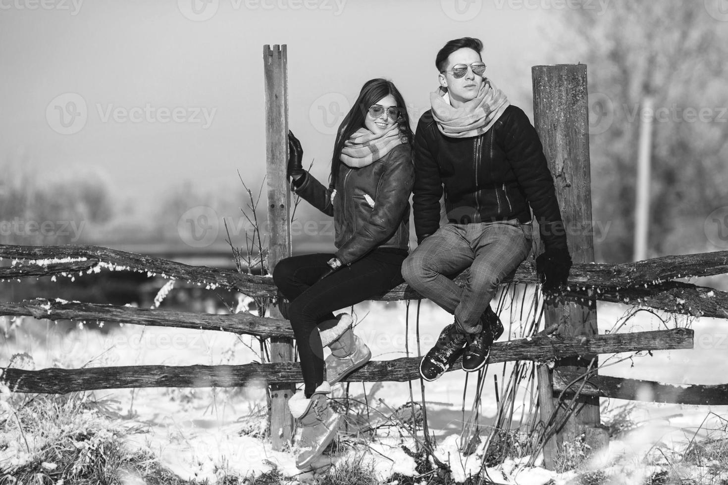 jovem casal sentado na cerca velha foto