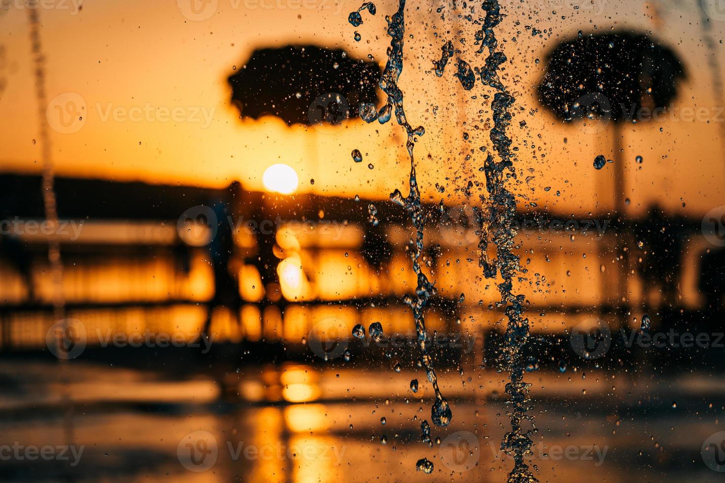 fluxo de uma fonte espirra água, pôr do sol foto