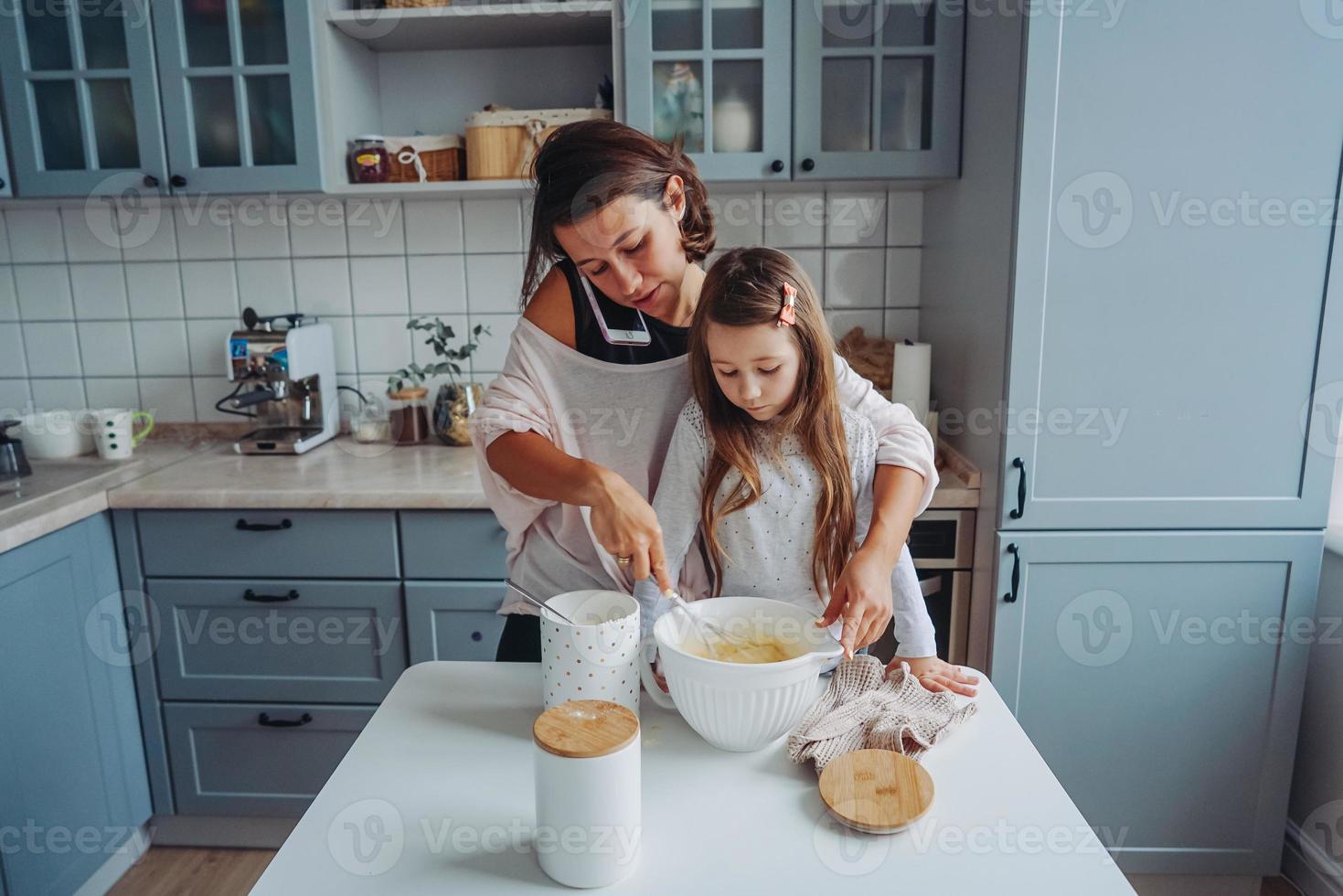 mãe ensina sua filha a cozinhar comida foto