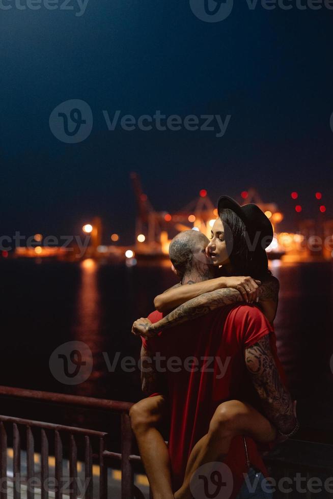 cara e garota se abraçando em um fundo do porto noturno foto