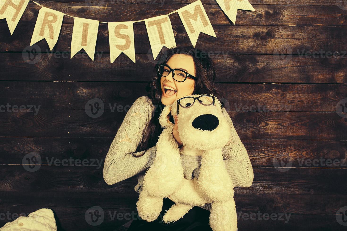 menina bonitinha abraçando um brinquedo fofo. fundo de natal foto