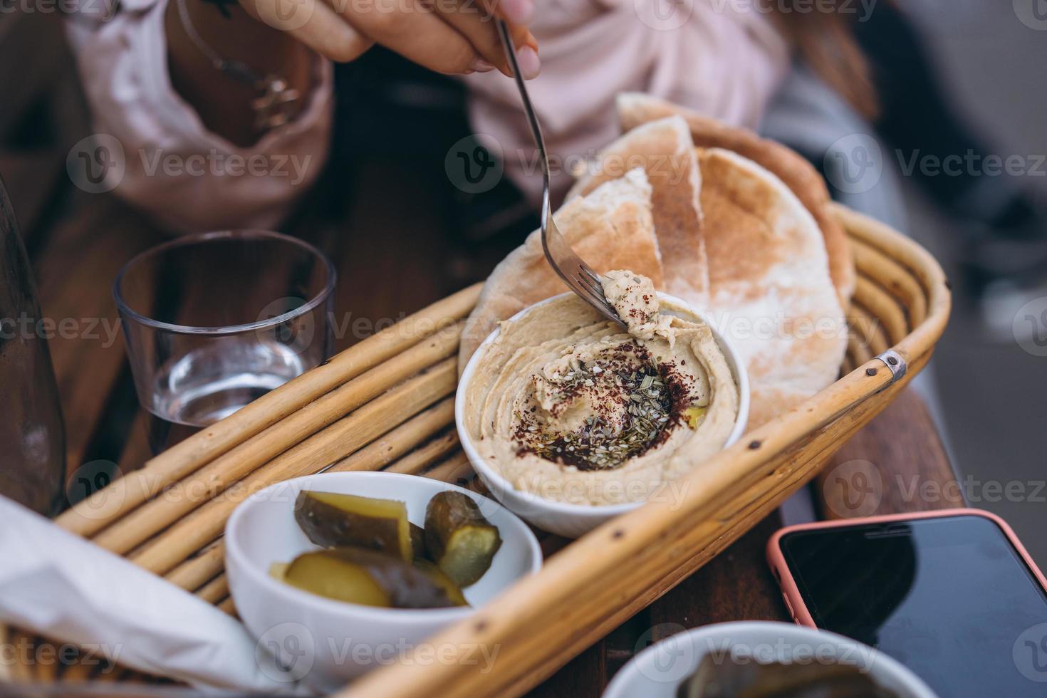 delicioso hummus fresco, pão pita e pepinos em conserva foto