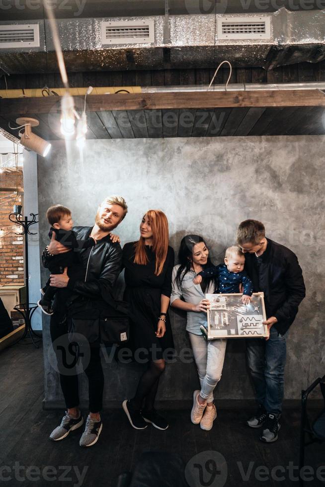 duas famílias jovens posando contra uma parede cinza foto