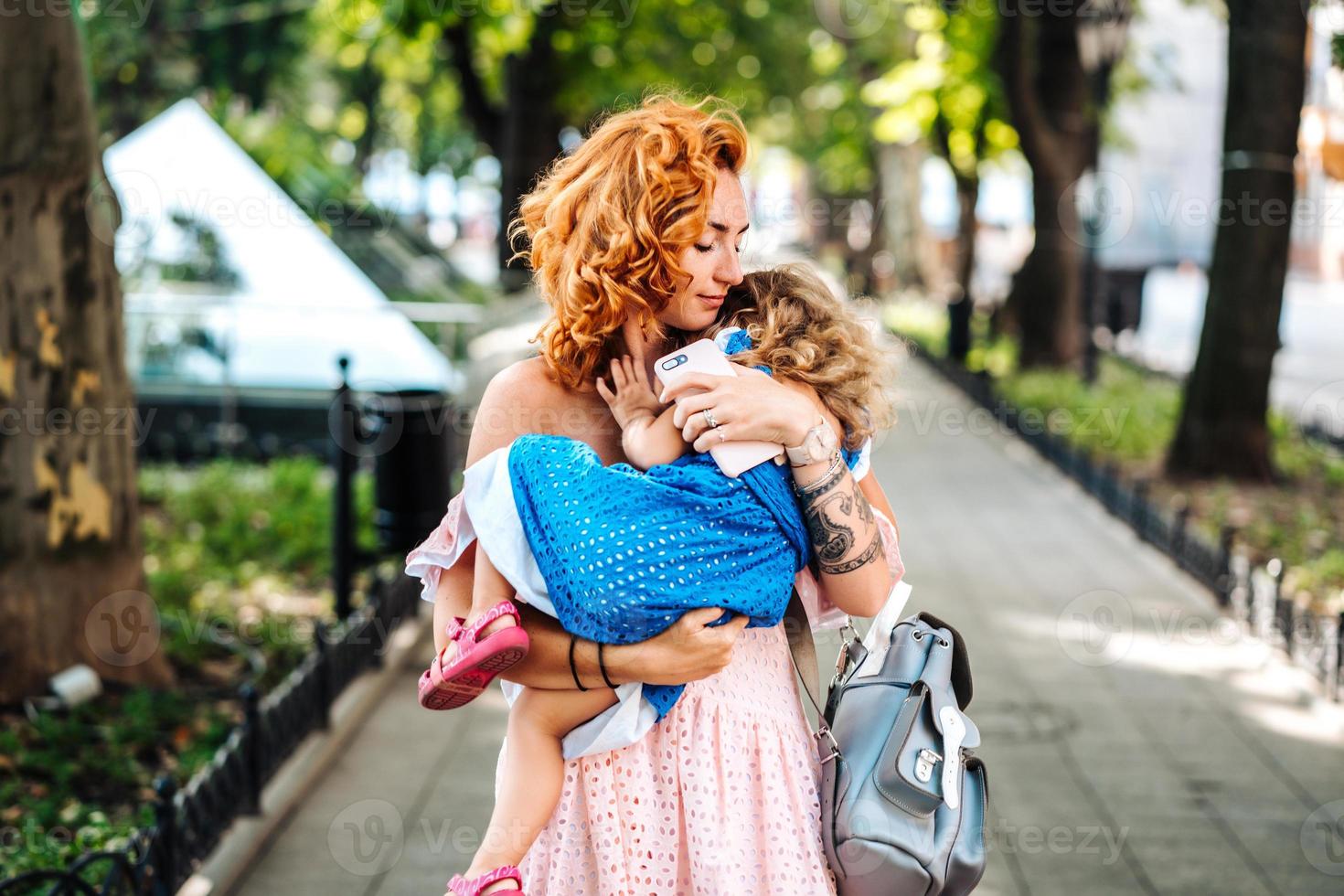 mulher abraça sua filha, segurando-a em seus braços foto