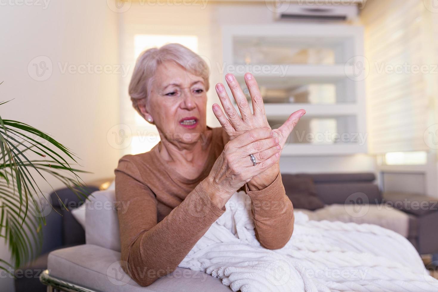 mulher idosa que sofre de dor na mão, artrite pessoa idosa e mulher idosa que sofre de dor em casa foto