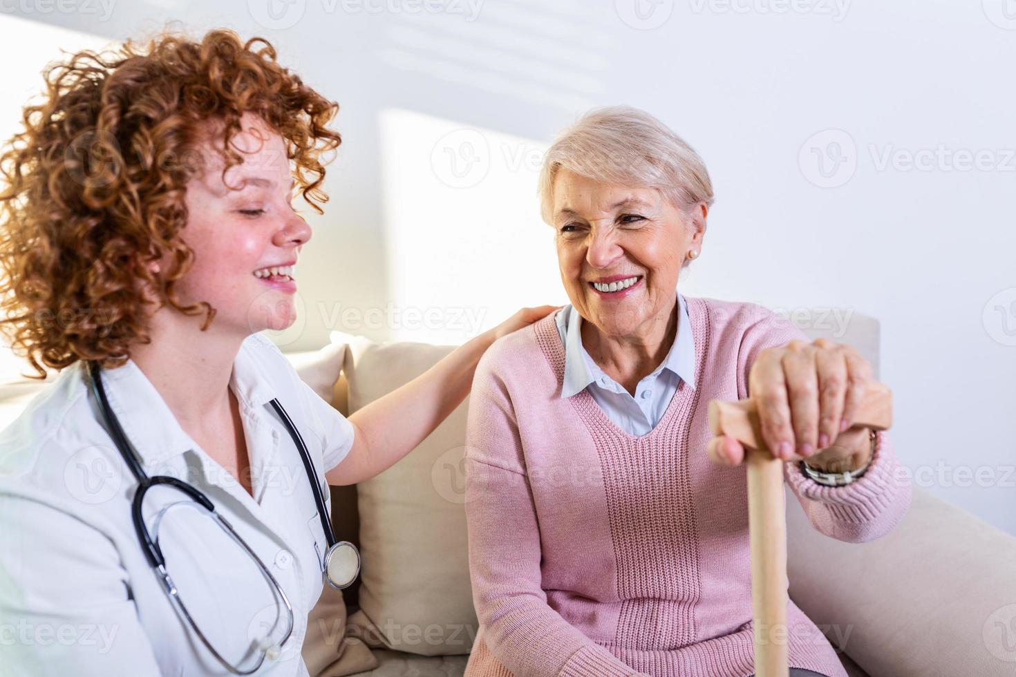 estreita relação positiva entre paciente idoso e cuidador. mulher sênior feliz falando com um cuidador amigável. jovem cuidadora bonita e mulher feliz mais velha foto