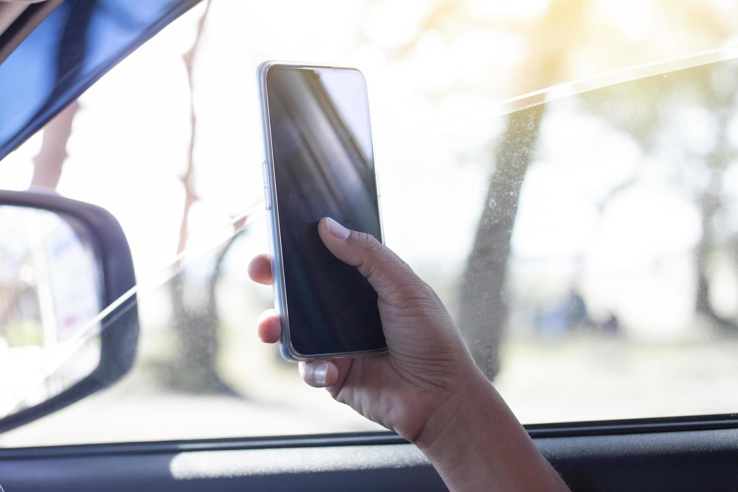 a mão do motorista está usando um telefone celular para ajudar a navegar ou gps enquanto estaciona na beira da estrada. foto