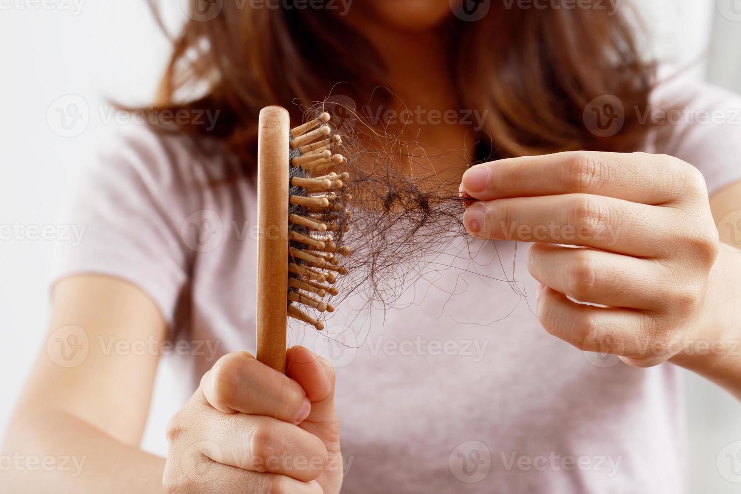 vista traseira jovem preocupada com problema de perda de cabelo, desequilíbrio hormonal, conceito de estresse. muitos cabelos caem depois de pentear na escova de cabelo na mão. fêmea desembaraçou o cabelo com um pente, cuidados de saúde foto