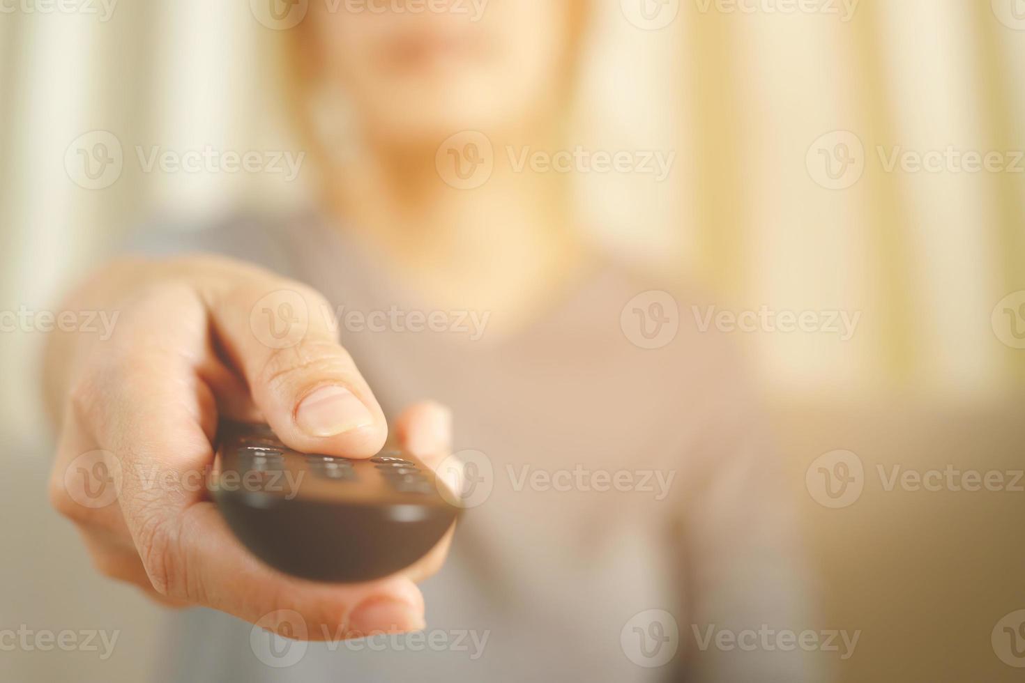 feche o controle remoto da televisão na mão de homem casual, apontando para o aparelho de tv e ligando ou desligando. selecione o canal assistindo jogo de futebol na tv dele em casa na sala de estar relaxe. foto