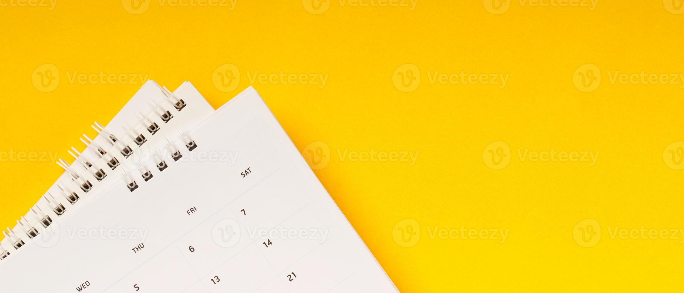 agenda do mês do calendário para fazer reuniões de compromisso ou gerenciar o cronograma a cada dia deitada e caneta em fundo amarelo para planejar o trabalho e o conceito de viagem. foto