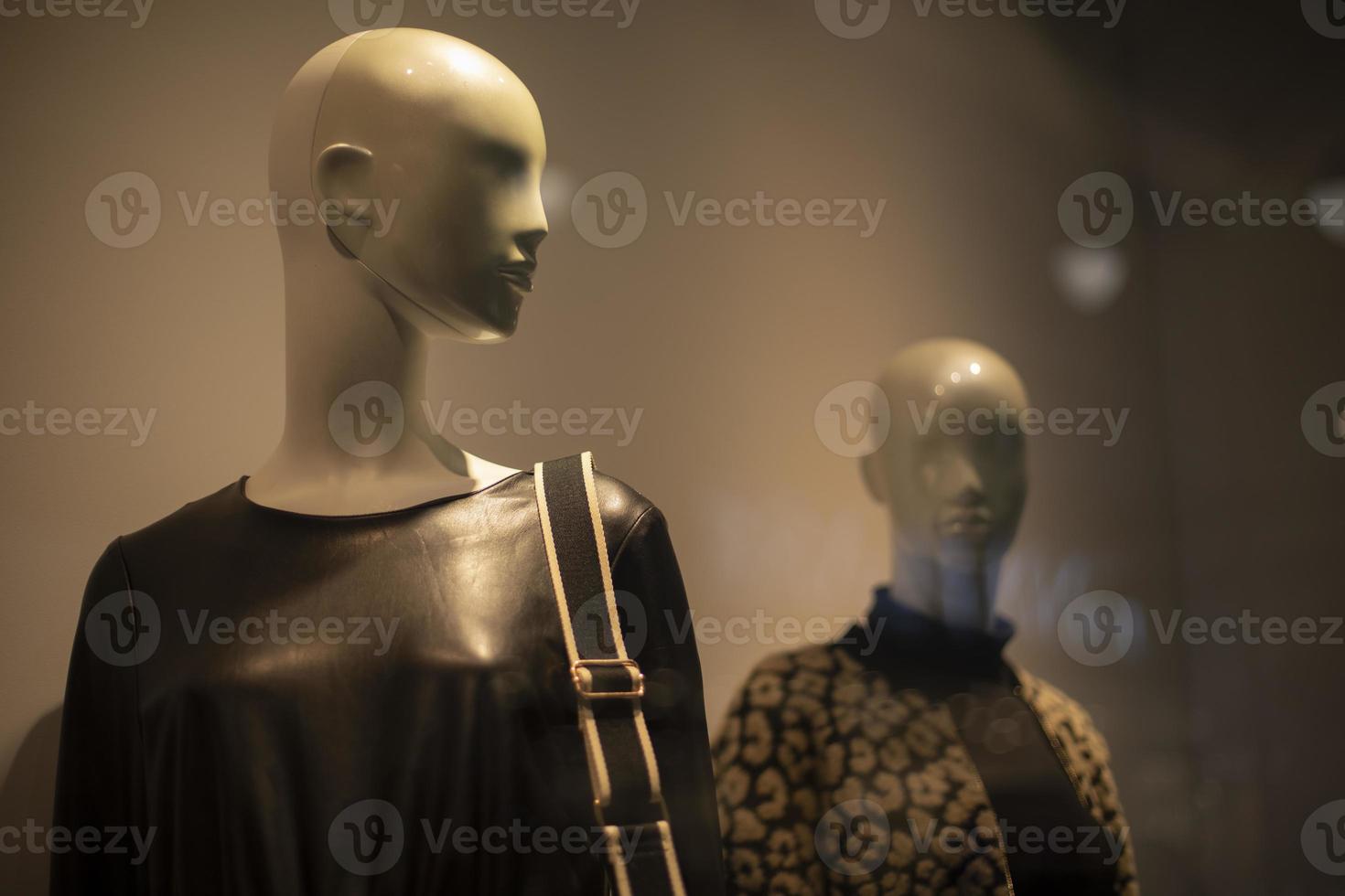 dois manequins femininos em uma loja de roupas. um manequim de jaqueta de couro e com uma bolsa no ombro. foto