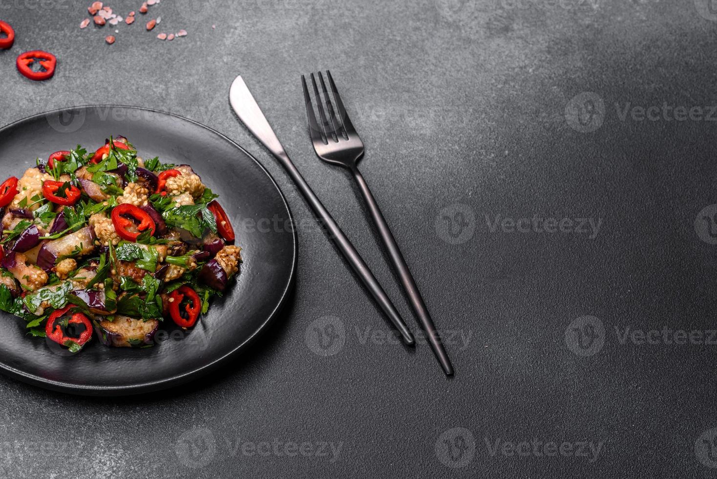 uma salada de berinjela assada, pimentão, alho, abobrinha e salsa em um prato preto foto