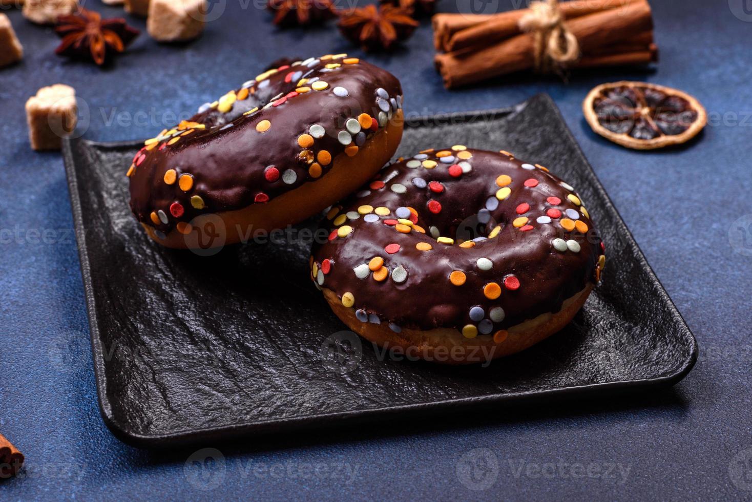 conceito de pastelaria. rosquinhas com cobertura de chocolate com granulado, em uma mesa de concreto escuro foto