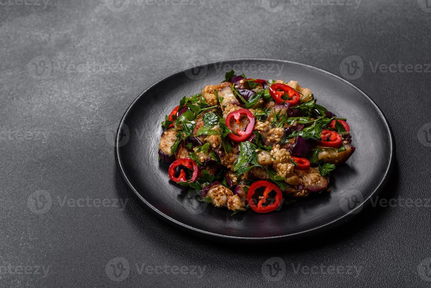 uma salada de berinjela assada, pimentão, alho, abobrinha e salsa em um prato preto foto