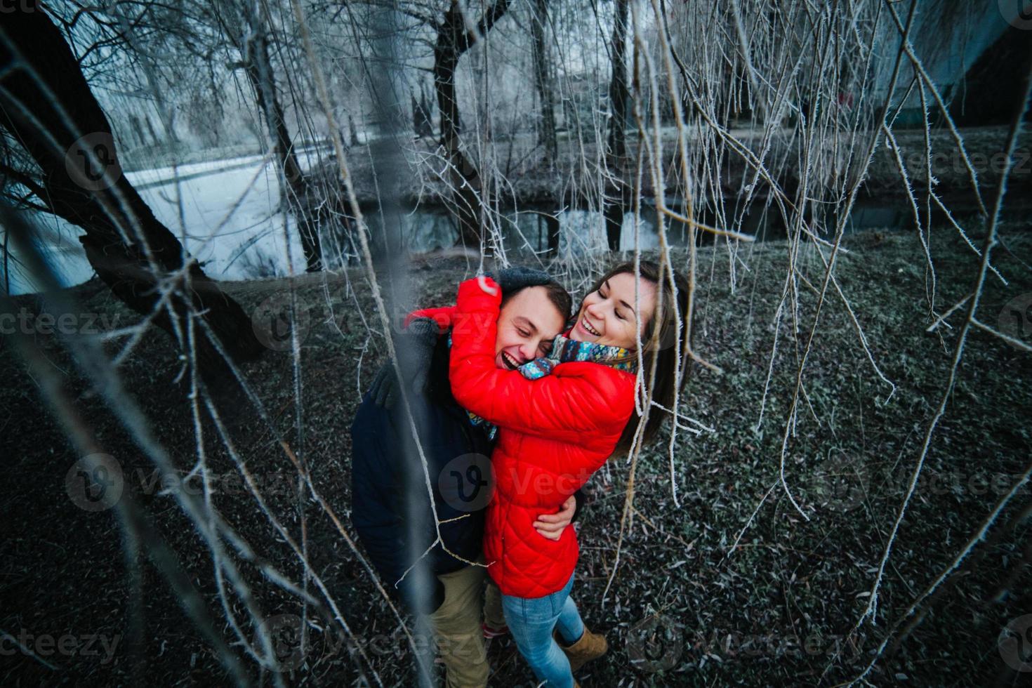 lindo casal posando perto de um rio congelado foto