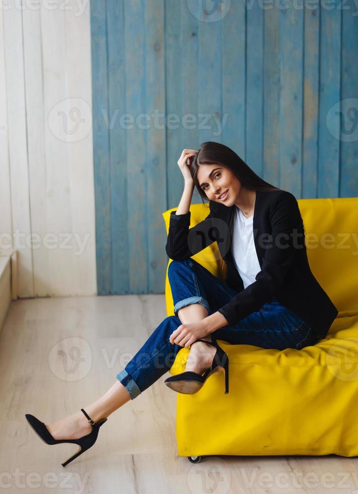 jovem sentada no sofá amarelo foto
