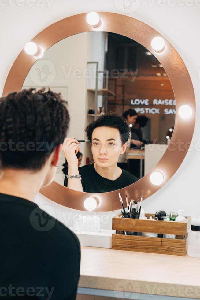 mulher atraente no espelho no estúdio de beleza foto