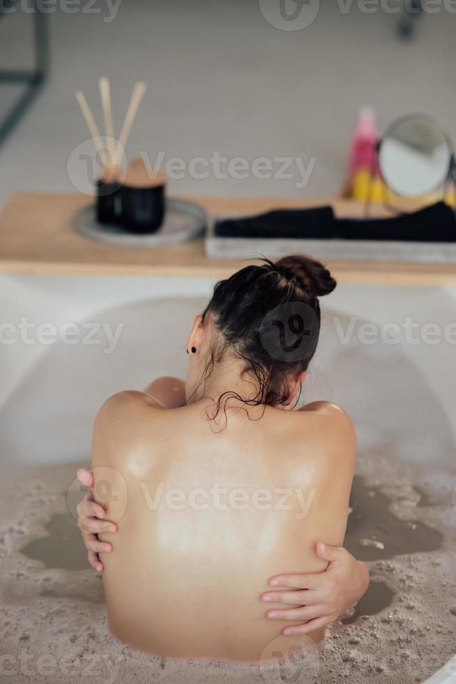 jovem mulher se abraçando tomando banho vista de trás foto