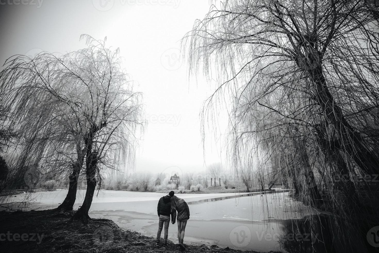 lindo casal posando perto de um rio congelado foto