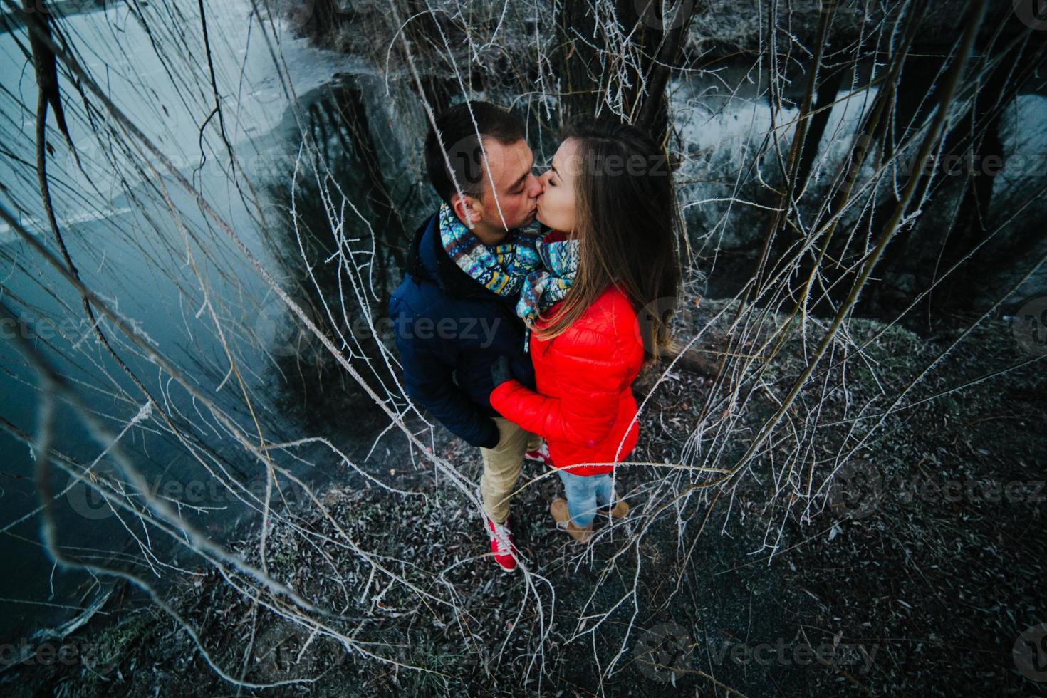 lindo casal posando perto de um rio congelado foto