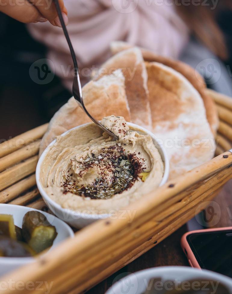 delicioso hummus fresco, pão pita e pepinos em conserva foto