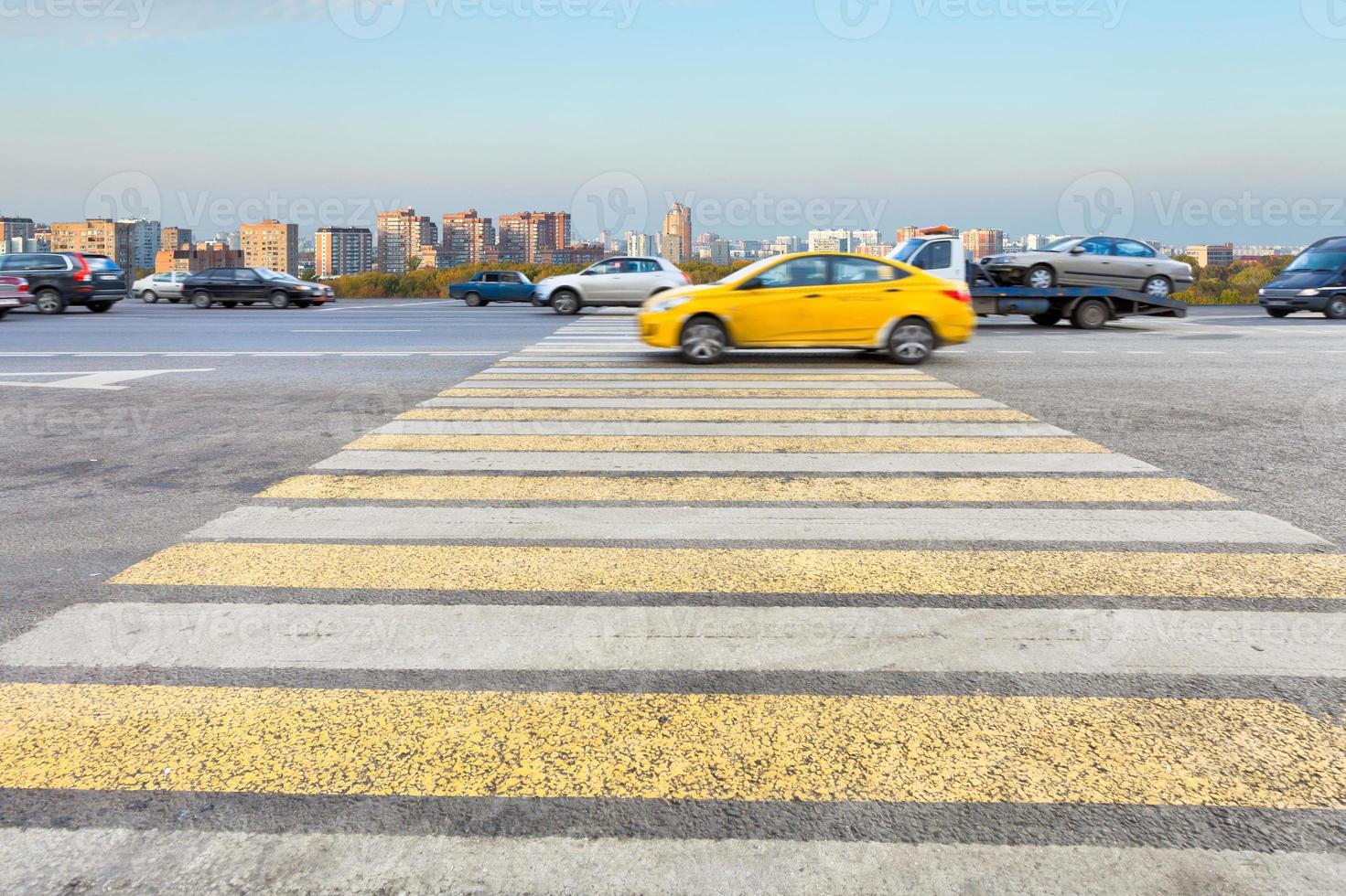 táxi na zebra de cruzamento amarela e branca na rua foto