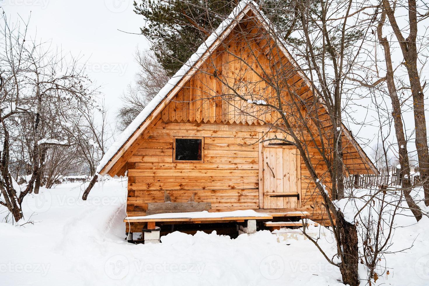 nova pequena casa de madeira no jardim coberto de neve foto