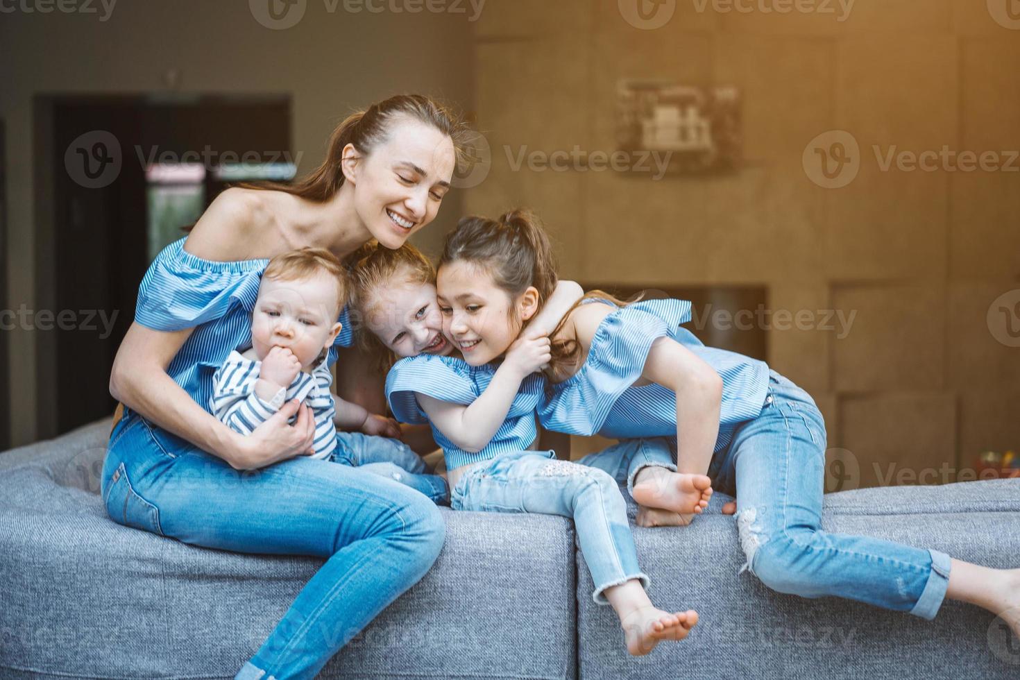 mãe, duas filhas e um filho pequeno no sofá foto