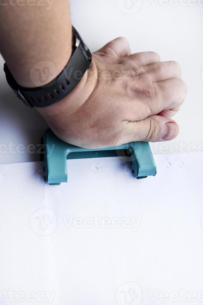 perfurador de furo verde à disposição em um fundo branco. close-up de artigos de papelaria. foto