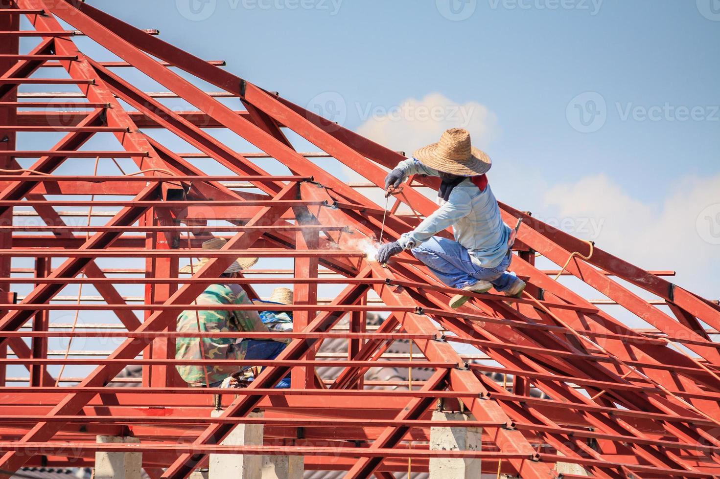 trabalhadores de solda instalando estrutura de armação de aço do telhado da casa no canteiro de obras foto