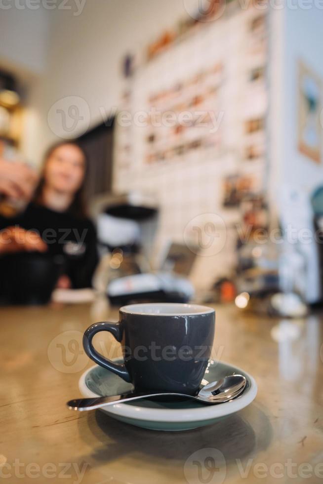 xícara de café preto, colher, mesa de madeira, em um café foto