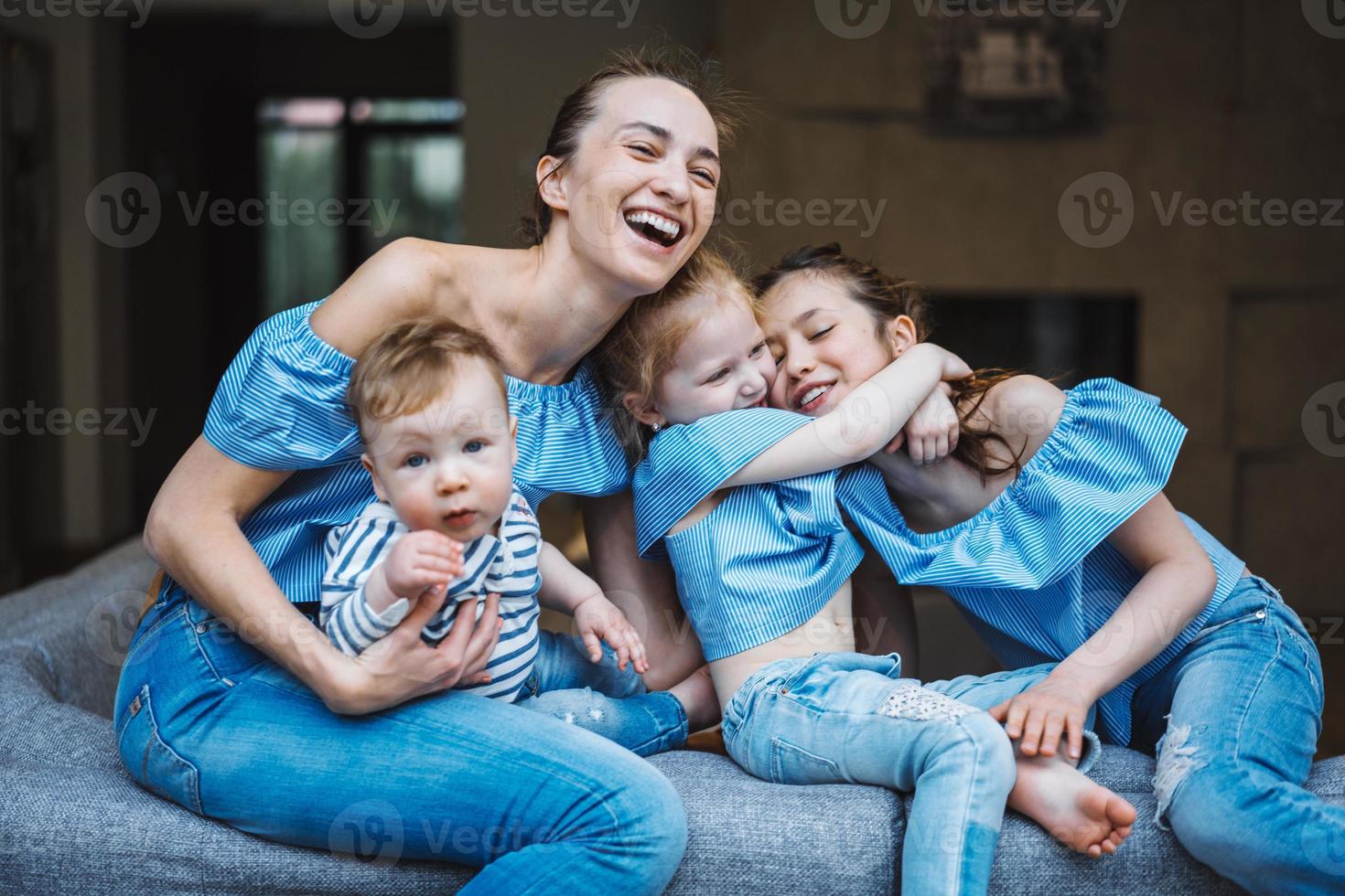 mãe, duas filhas e um filho pequeno no sofá foto