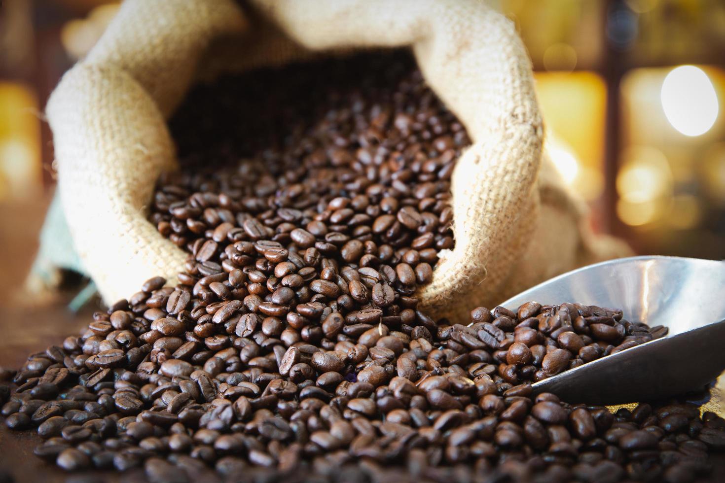 grãos de café em um saco na mesa escura. foto